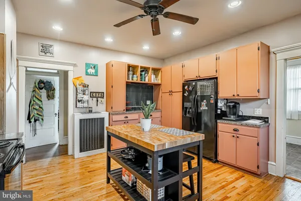 a kitchen with stainless steel appliances kitchen island granite countertop a refrigerator a stove top oven a sink dishwasher and white cabinets with wooden floor