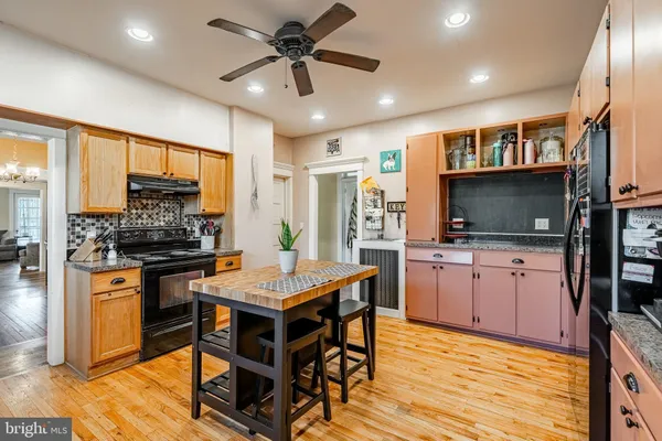 a kitchen with stainless steel appliances granite countertop a stove top oven a sink dishwasher a dining table and chairs with wooden floor