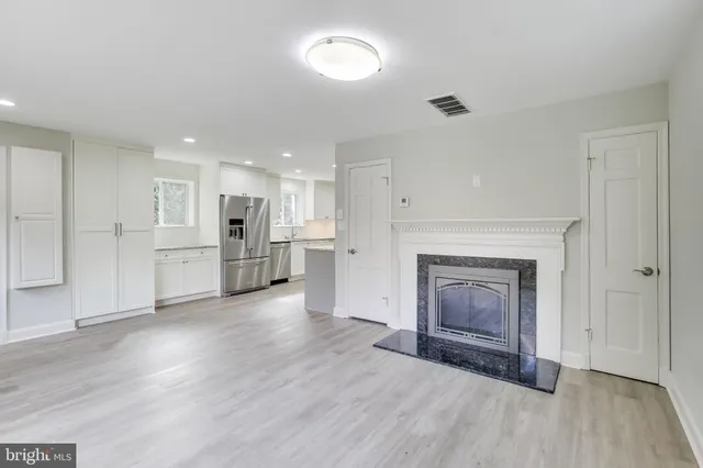 a view of a livingroom with a fireplace a ceiling fan and window
