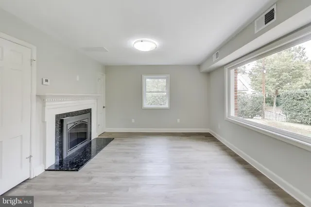 wooden floor fireplace and windows in an empty room