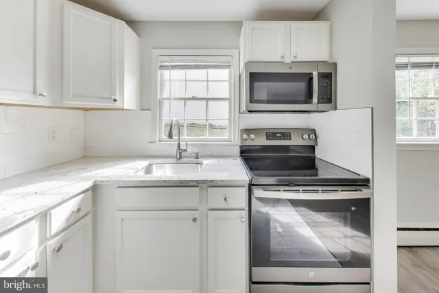 a kitchen with granite countertop a stove sink and microwave