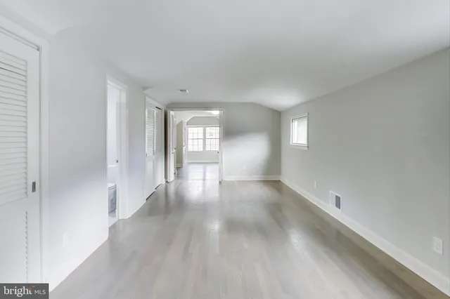 a view of an empty room with window and wooden floor