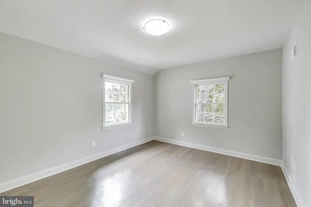 an empty room with wooden floor and window