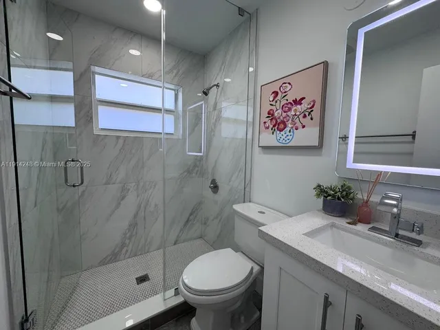 a bathroom with a granite countertop toilet sink and mirror