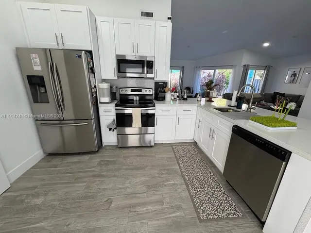 a kitchen with stainless steel appliances a stove a refrigerator and a sink