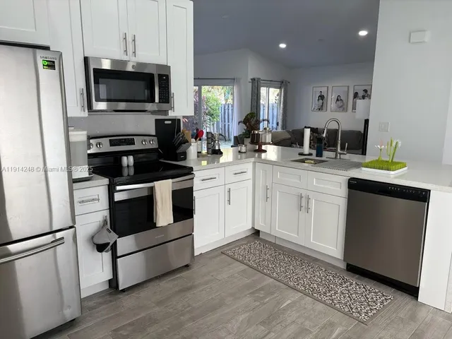 a kitchen with cabinets stainless steel appliances and wooden floor