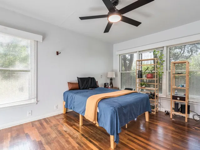 a bedroom with a bed and a large window with wooden floor