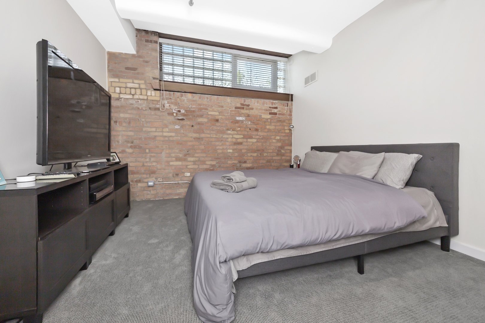 1000 West Washington Boulevard, Unit 142 Chicago, IL 60607 - Photo 17 of 24 a bedroom with a bed and a flat tv screen next to a window