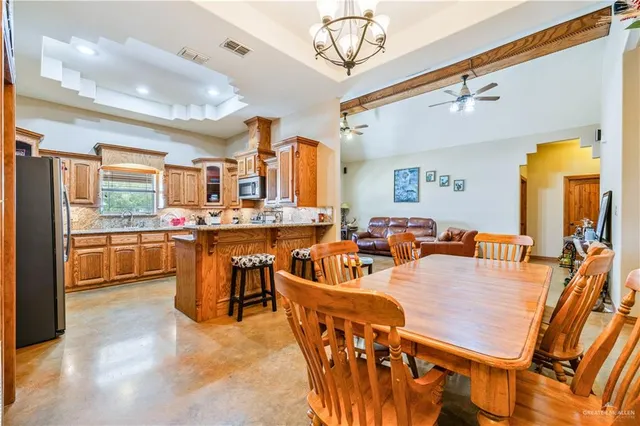 a living room with stainless steel appliances furniture a chandelier and a view of kitchen
