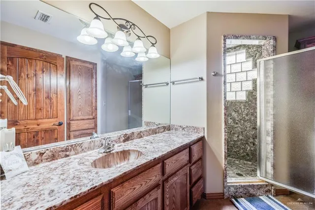 a bathroom with a granite countertop double vanity and a mirror