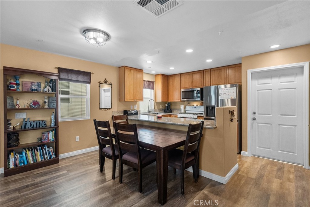 26135 Gravett Place Saugus, CA 91350 - Photo 9 of 31 a kitchen with stainless steel appliances granite countertop a dining table chairs refrigerator and sink