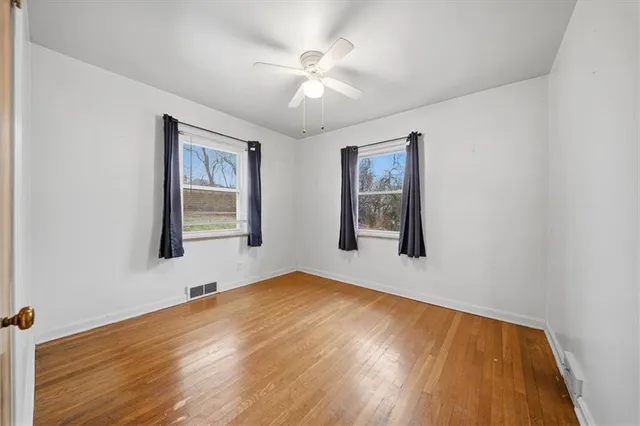 a view of an empty room with window and wooden floor