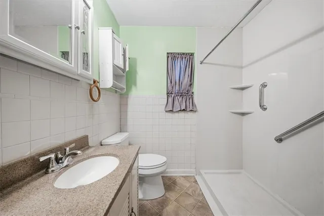 a bathroom with a granite countertop sink toilet and shower