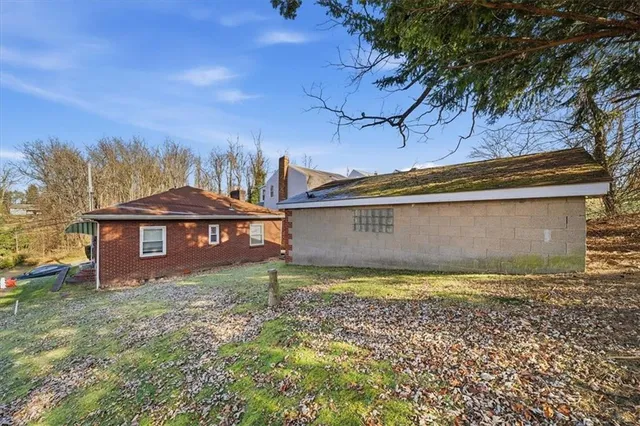 a view of a house with a yard and large tree and a wooden fence