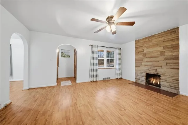 an empty room with wooden floor fireplace and windows