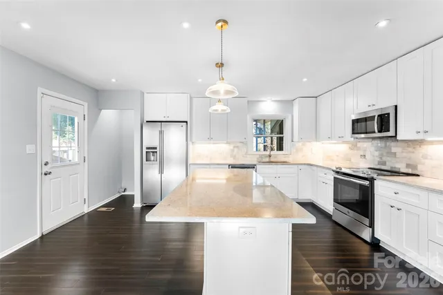 a large kitchen with granite countertop a stove oven and a sink