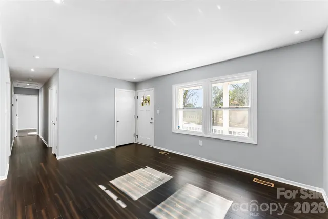a view of an empty room with a window and wooden floor