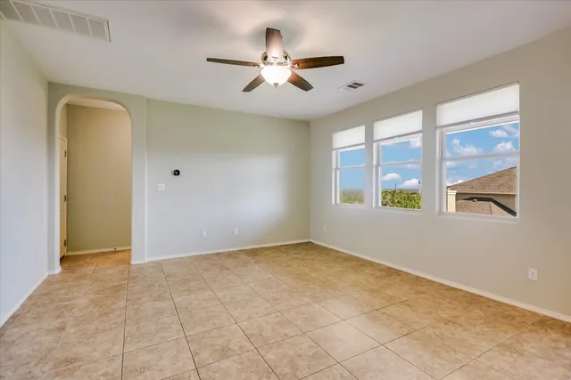 an empty room with windows and ceiling fan
