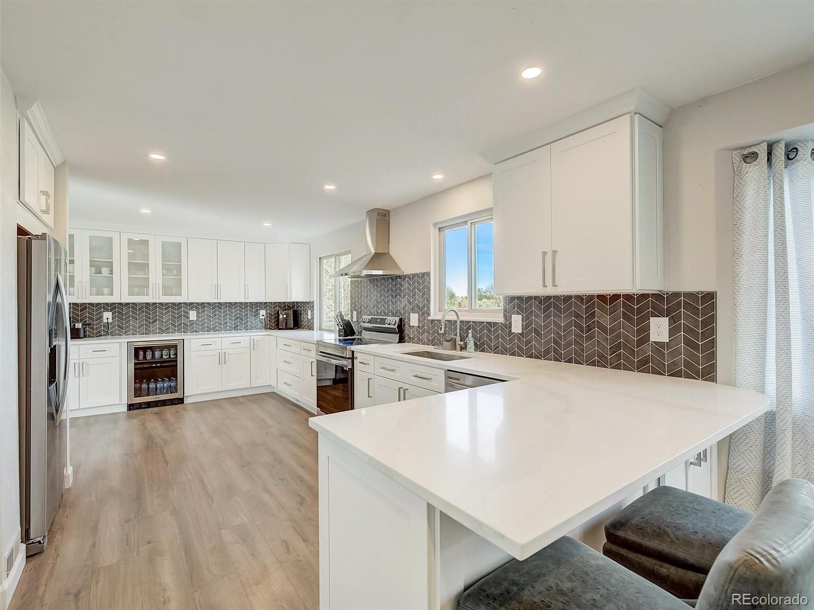 6432 South Birch Circle Centennial, CO 80121 - Photo 5 of 40 a large kitchen with kitchen island a stove a sink a refrigerator and white cabinets