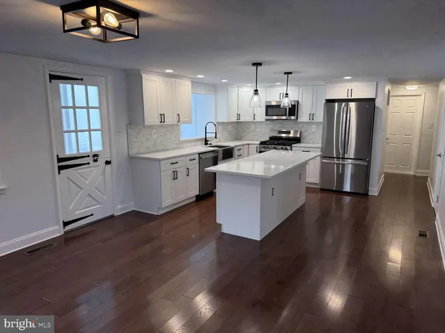 a kitchen with a refrigerator a sink dishwasher a stove and a refrigerator with wooden floor