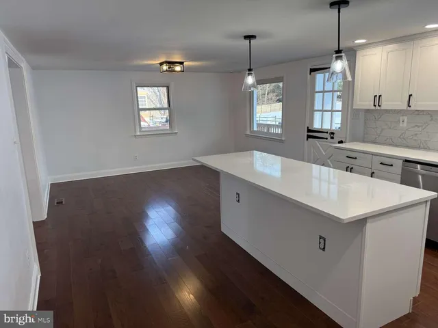 a kitchen with a sink a center island a wooden floor and a window