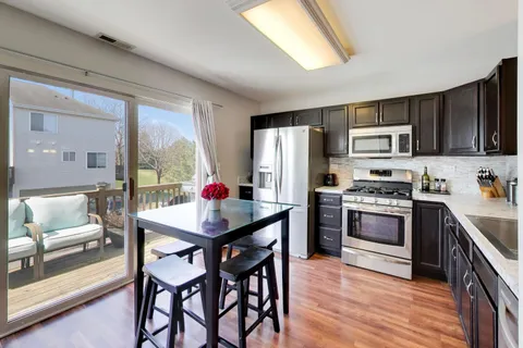 a kitchen with stainless steel appliances kitchen island granite countertop a refrigerator a stove a sink and dishwasher with wooden floor