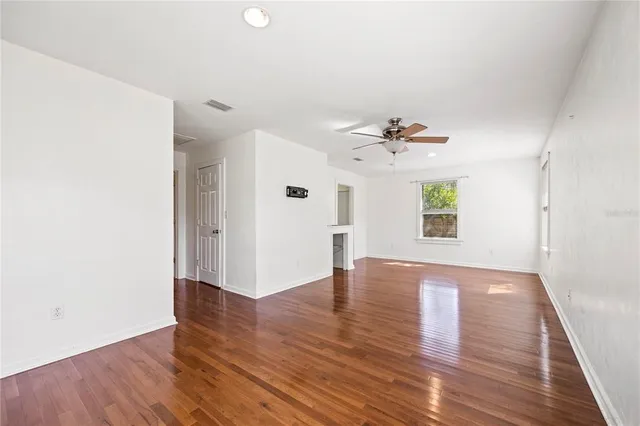 a view of an empty room with a window and wooden floor