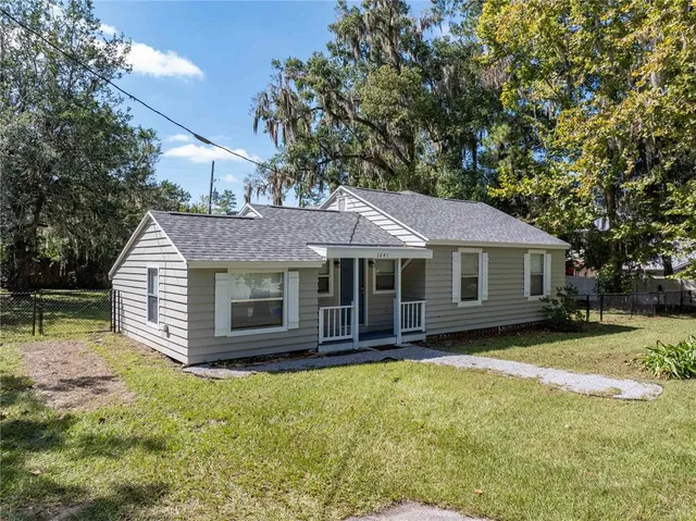 a view of a house with a yard and large tree