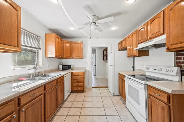 a kitchen with stainless steel appliances granite countertop a sink a stove a refrigerator cabinets and a dining table