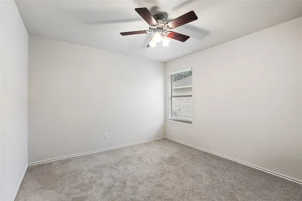 an empty room with a ceiling fan and a window