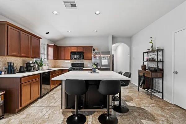 a kitchen with stainless steel appliances kitchen island granite countertop a table chairs sink and cabinets