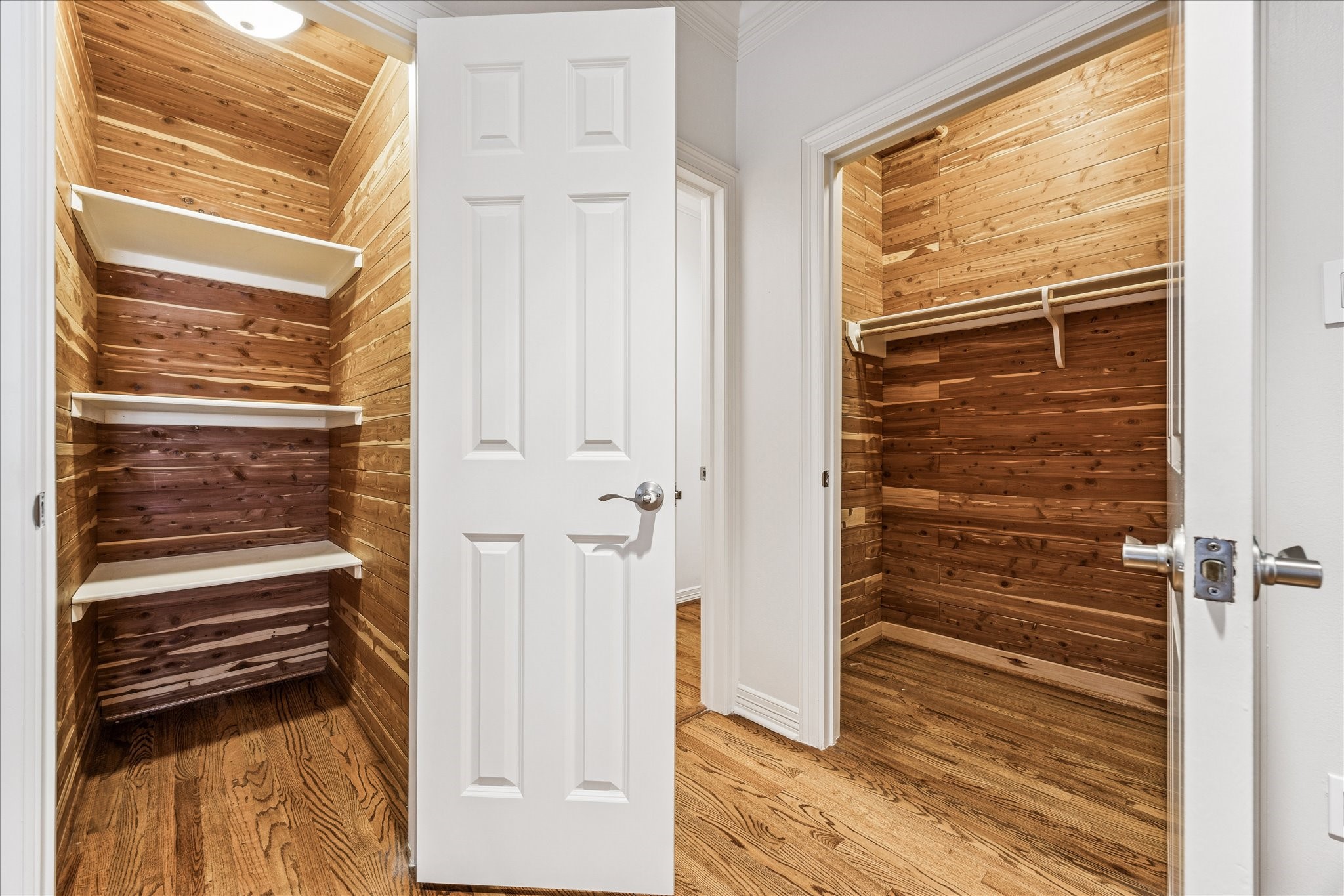 5823 Augusta Court Houston, TX 77057 - Photo 40 of 44 Located on the second floor landing these two spacious closets with beautiful wood paneling and hardwood floors. One closet features multiple white shelves, while the other has a hanging rod, offering ample storage options.