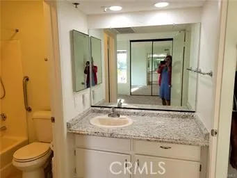a bathroom with a granite countertop sink a toilet and a mirror