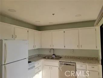 a kitchen with granite countertop a sink a stove and white cabinets