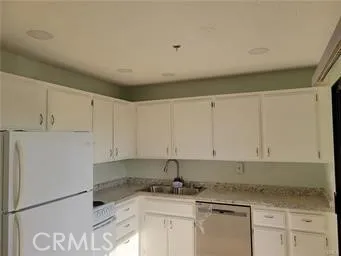 a kitchen with granite countertop a sink a stove and white cabinets
