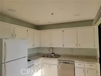 a kitchen with granite countertop a sink a stove and white cabinets