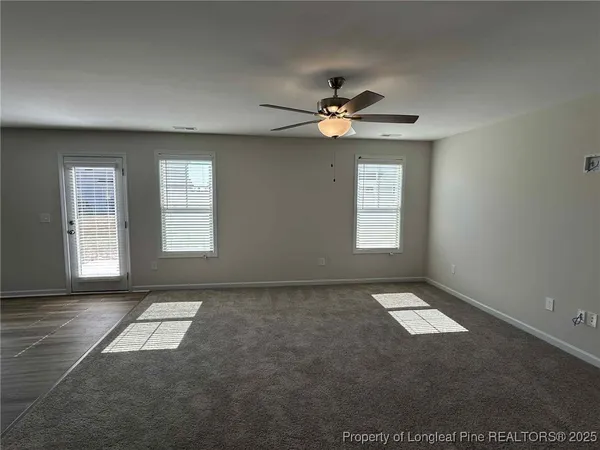 an empty room with windows and ceiling fan