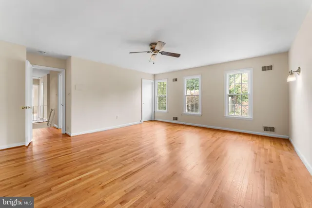 a view of empty room with wooden floor and ceiling fan
