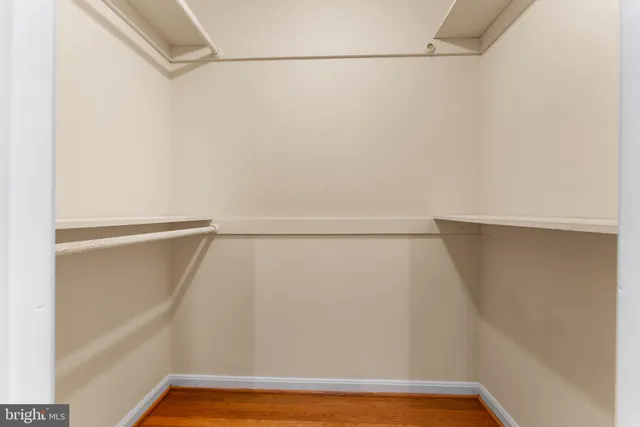 a view of an empty room with wooden floor and window