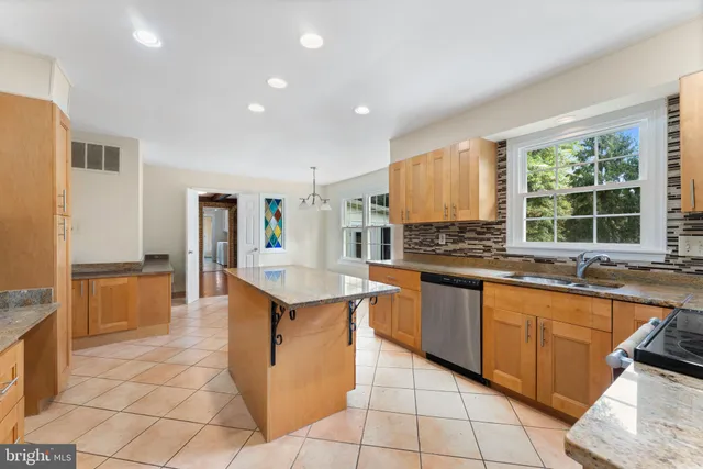 a kitchen with stainless steel appliances granite countertop a sink counter space and a view of living room