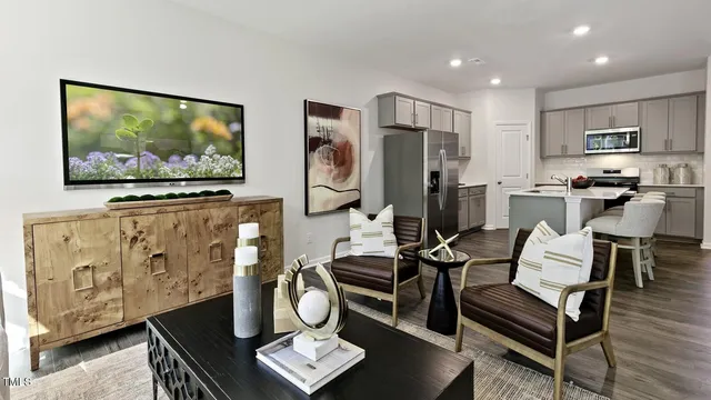 a living room with furniture a flat screen tv and kitchen view