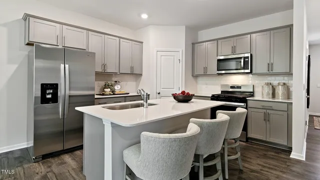 a kitchen with a refrigerator a sink a stove a table and chairs