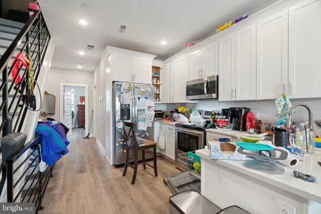a view of a kitchen with stainless steel appliances granite countertop a refrigerator sink dishwasher and a stove with wooden floor