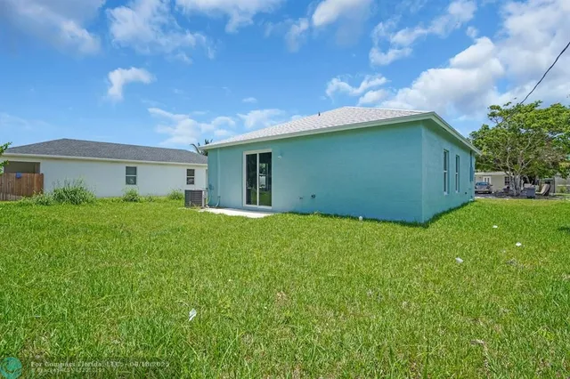 a backyard of a house with plants and large tree