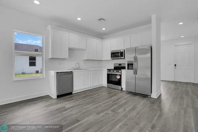 a kitchen with a refrigerator a stove top oven a sink and cabinets