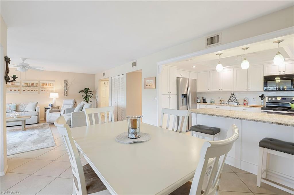 84 Georgetown Boulevard, Unit 84 Naples, FL 34112 - Photo 5 of 17 a dining room with kitchen island a table and chairs