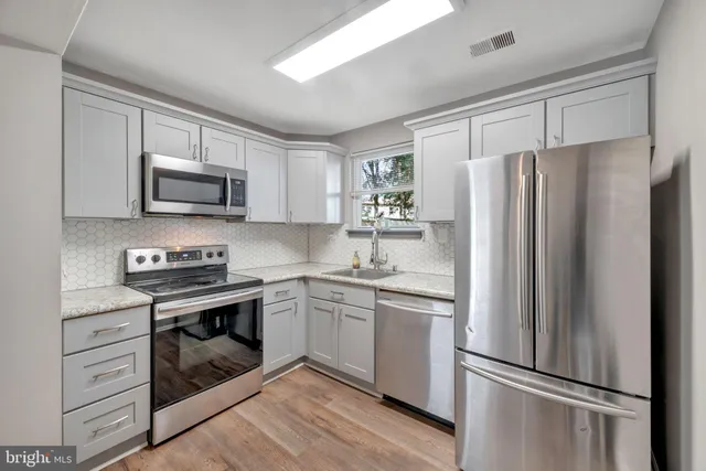 a kitchen with stainless steel appliances granite countertop a refrigerator stove and sink
