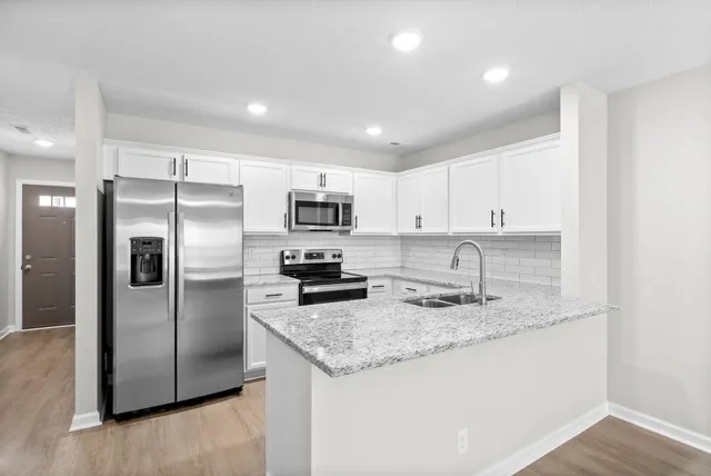 a kitchen with granite countertop kitchen island a refrigerator sink and microwave