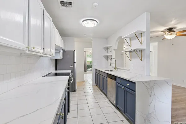 a kitchen with granite countertop a sink a stove top oven and cabinets