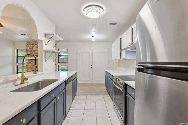 a kitchen with granite countertop a sink stainless steel appliances a counter space and a sink